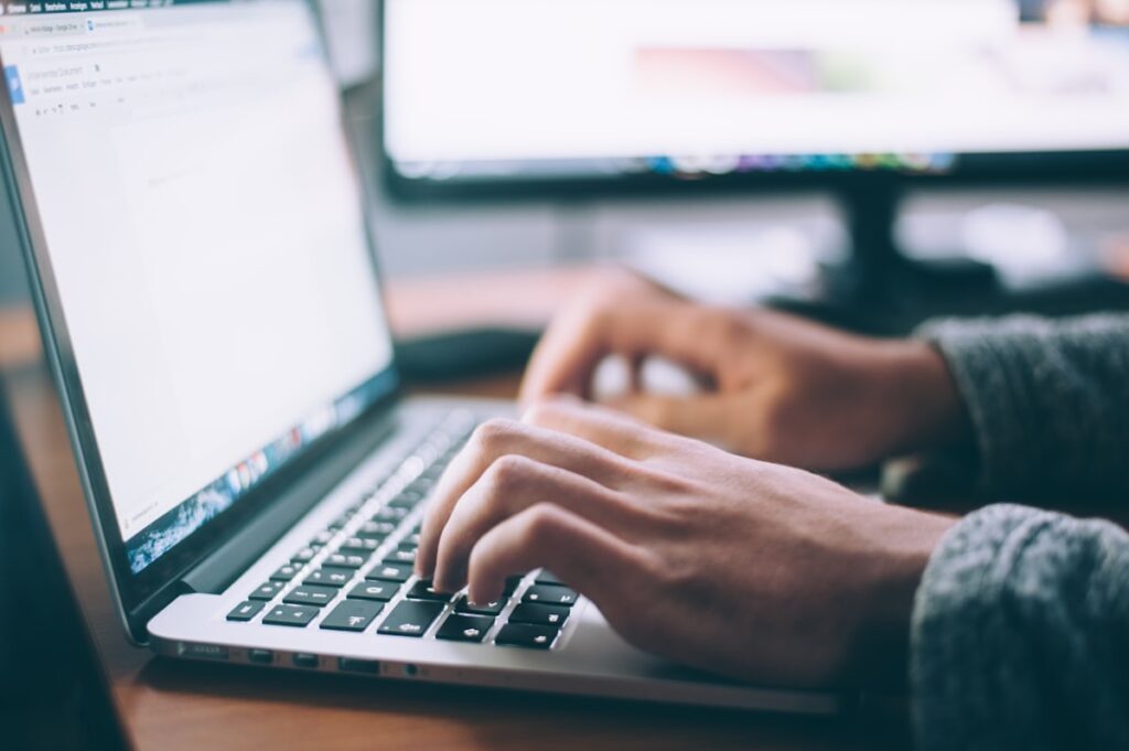 Person typing on laptop - AI writing tools comparison